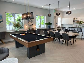 A pool table is in the middle of a room with chairs around it.